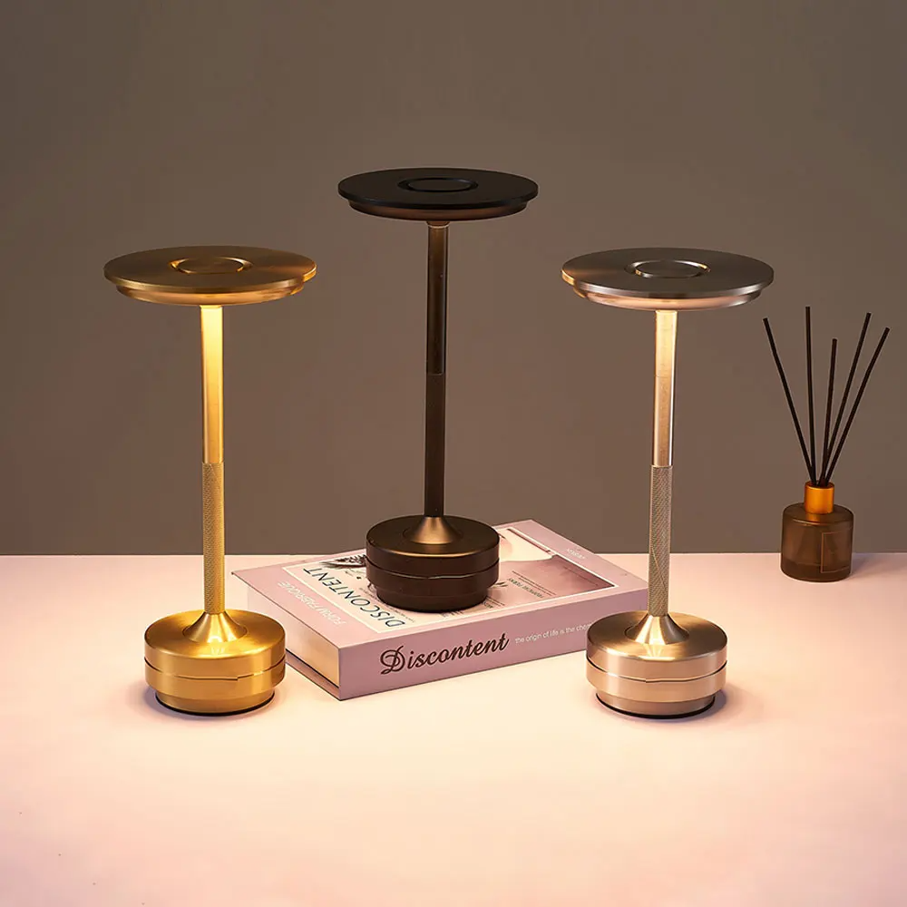 Three metallic candle holders on a table with a book and diffuser in the background.