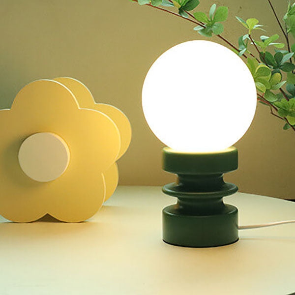 Two table lamps, one yellow and one green, on a surface with a blurred background.