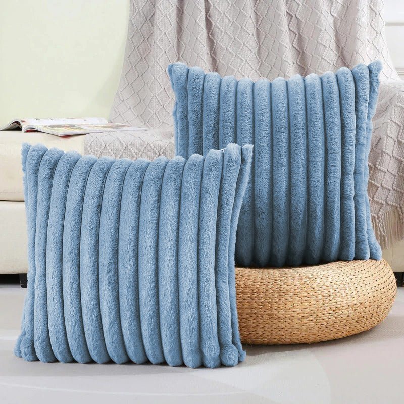 Two blue textured pillows on a couch with a neutral background