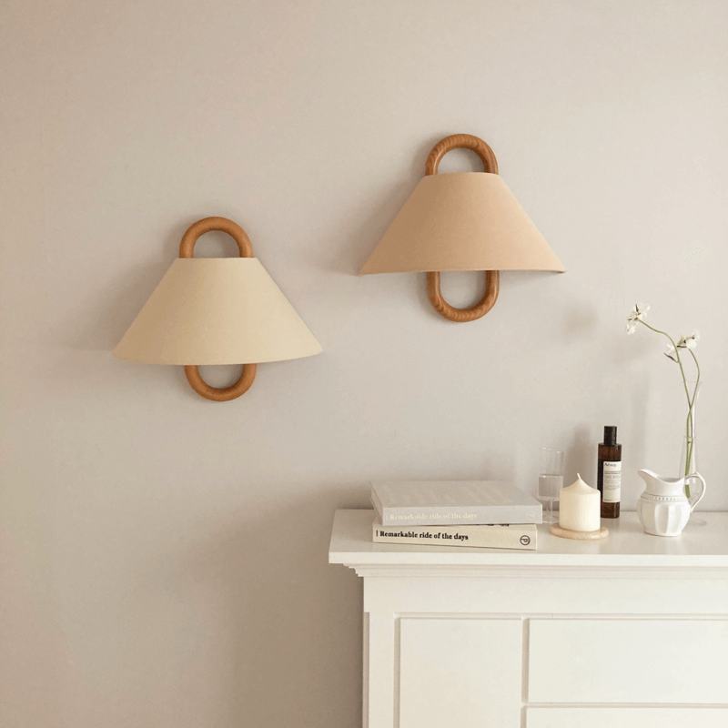 Two wall-mounted lamps with beige shades and wooden handles on a light gray wall.