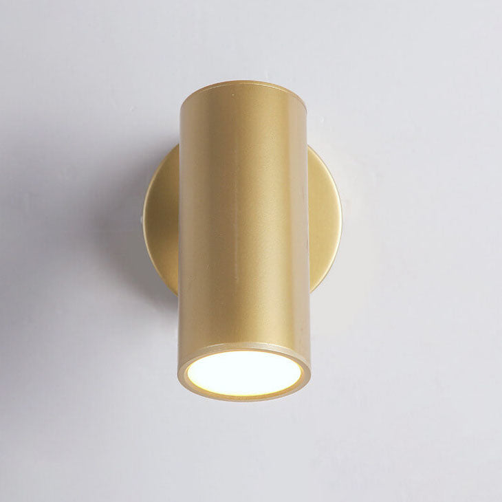 Gold cylindrical wall light fixture on a gray background