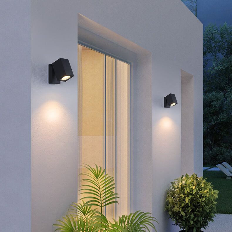 Modern outdoor wall lights on a house exterior with plants and a garden.