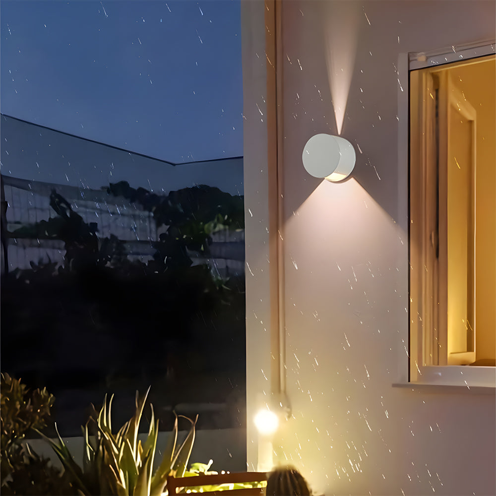 Outdoor wall light fixture on a building exterior with garden and night sky in the background