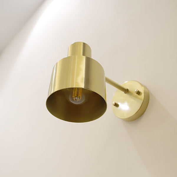 Gold wall-mounted light fixture on a white wall