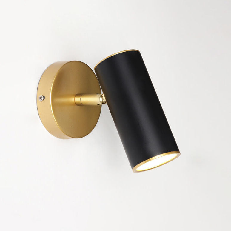 Wall-mounted light fixture with black cylindrical shade and gold base on a white background