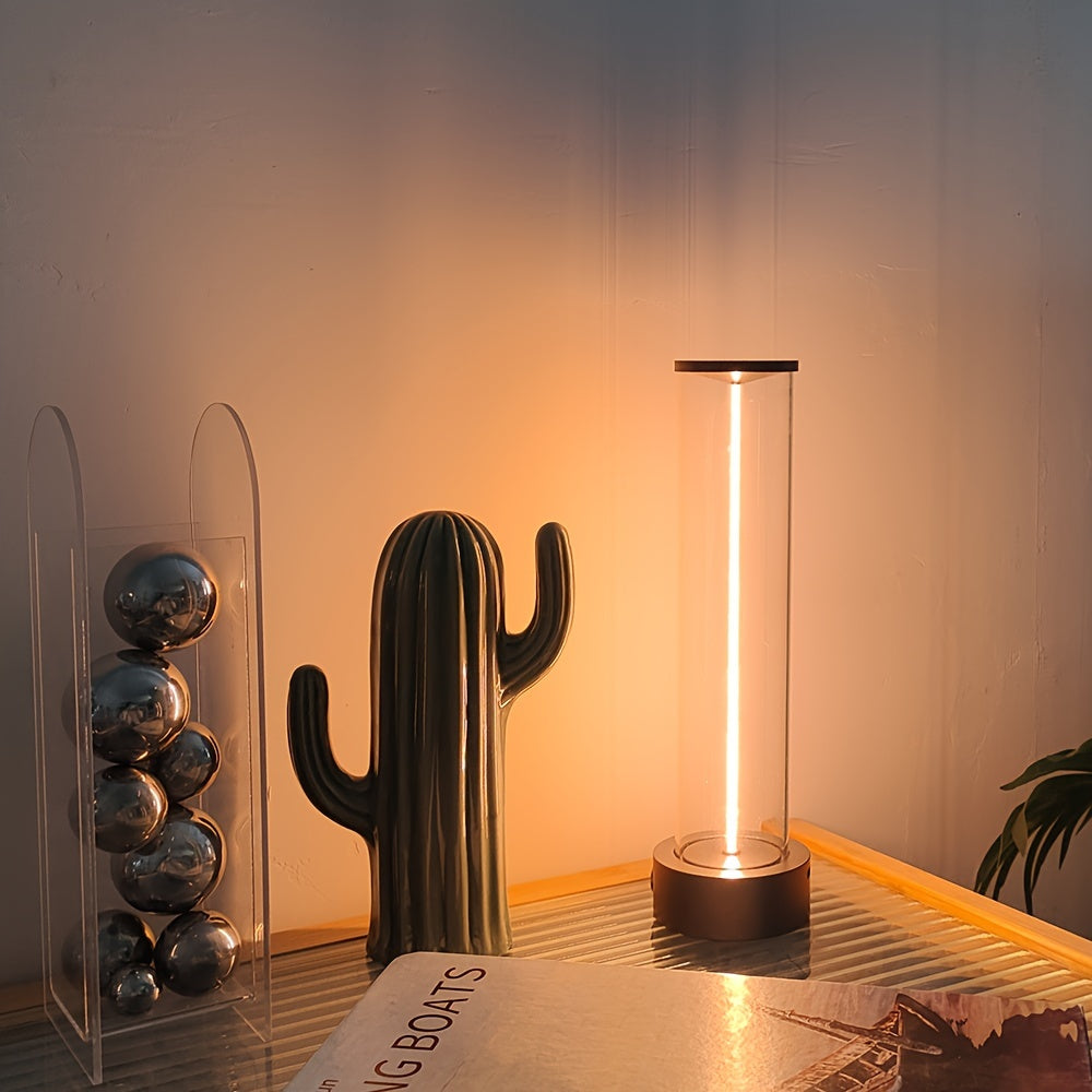 Decorative cactus sculpture and cylindrical lamp on a reflective surface with a warm glow.
