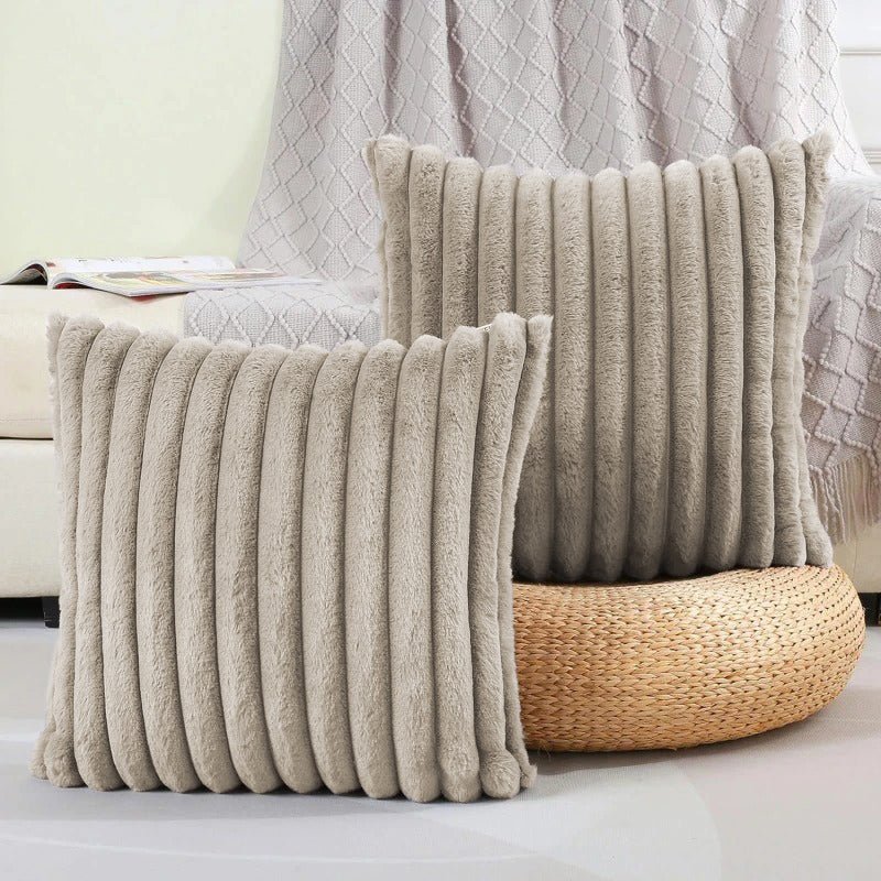 Two beige textured pillows on a couch with a woven basket in the background.