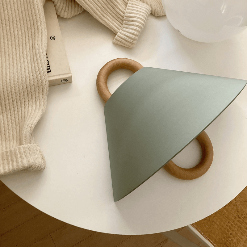Green triangular shelf with wooden handles on a white surface