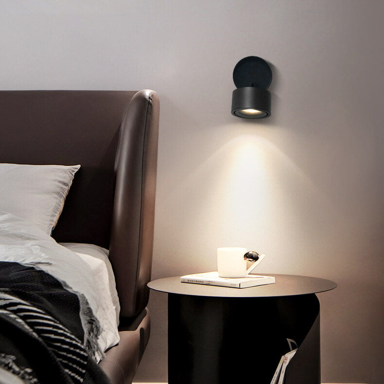 Modern bedroom with a bed, nightstand, and wall-mounted light fixture.