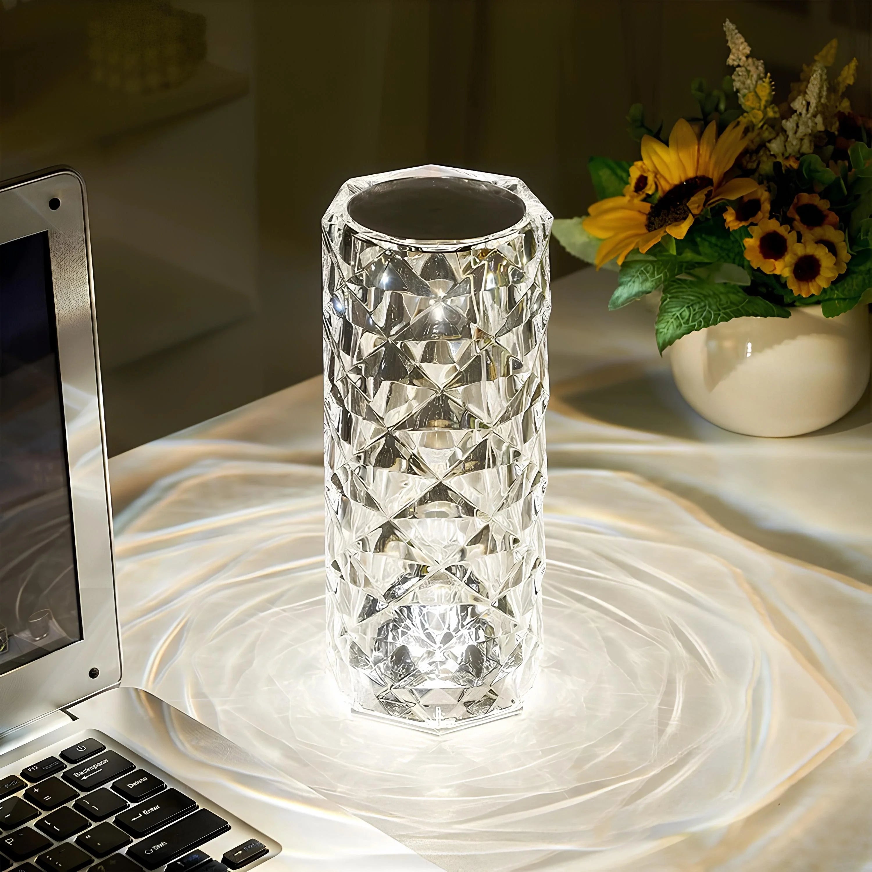 Crystal vase on a desk next to a laptop and sunflower arrangement