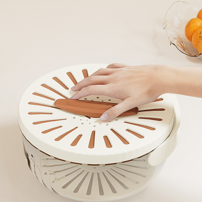 Person using a white salad spinner with wooden handle on a light background