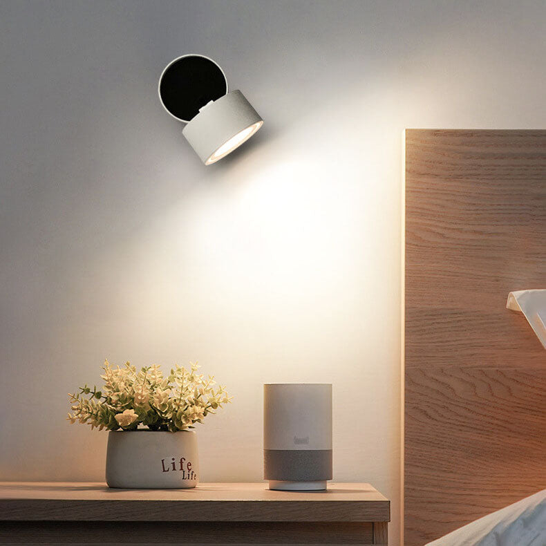 Modern wall-mounted light fixture on a neutral wall with a wooden shelf and decorative items.