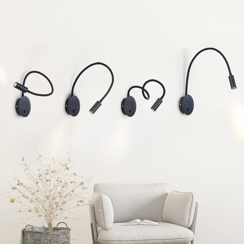 Four black wall-mounted lamps on a white wall above a gray sofa.