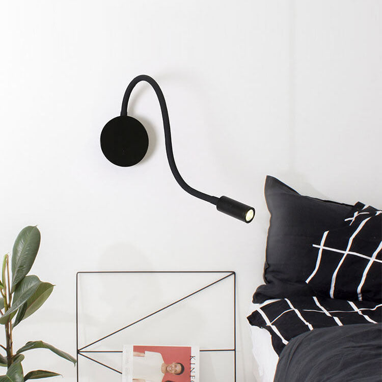 Black wall-mounted lamp next to a bed with black and white bedding