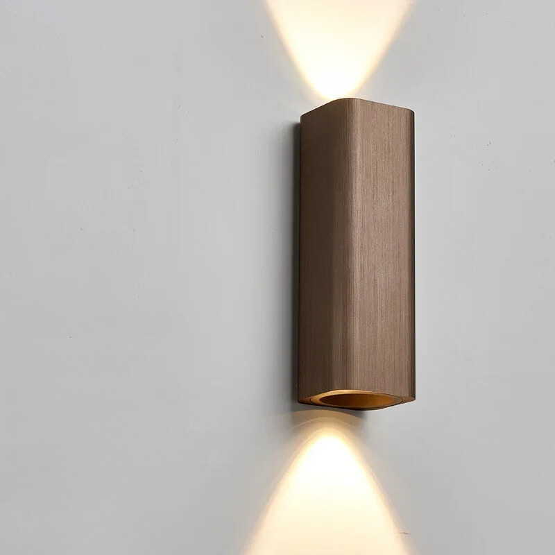 Bronze wall-mounted light fixture on a gray wall