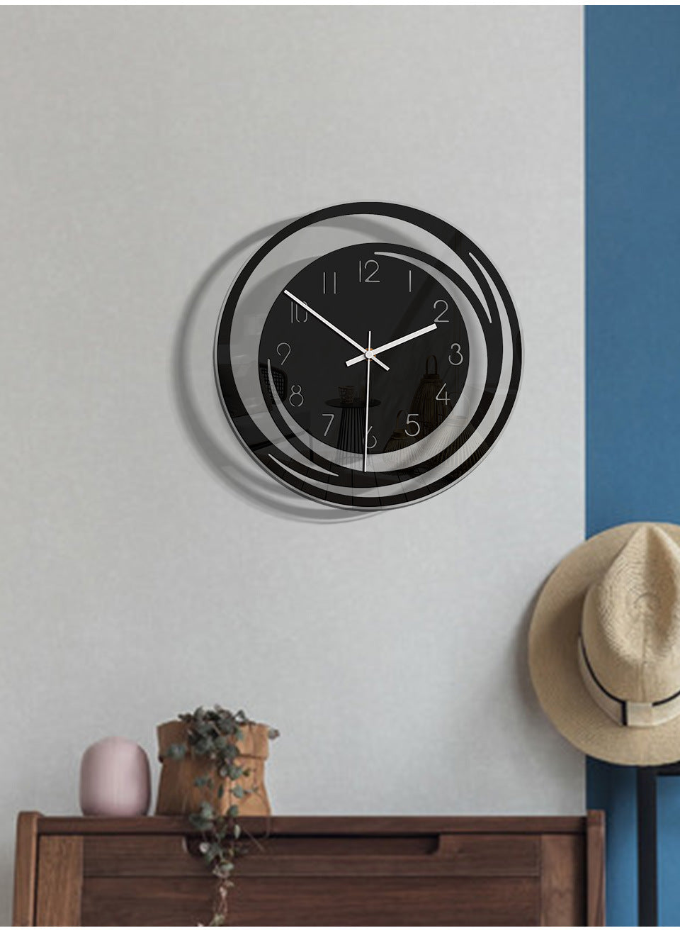 Wall clock on a wall with a hat and plant below