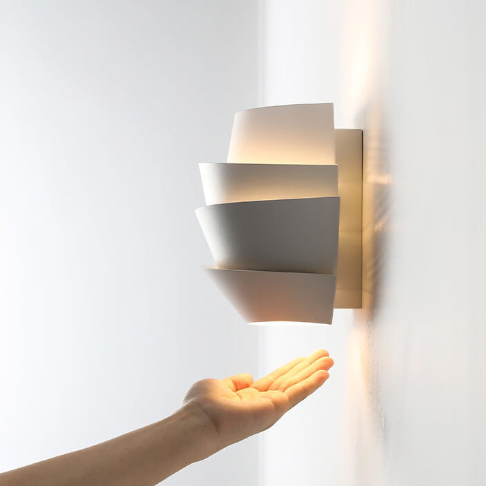Modern wall sconce with a hand reaching towards it on a white background