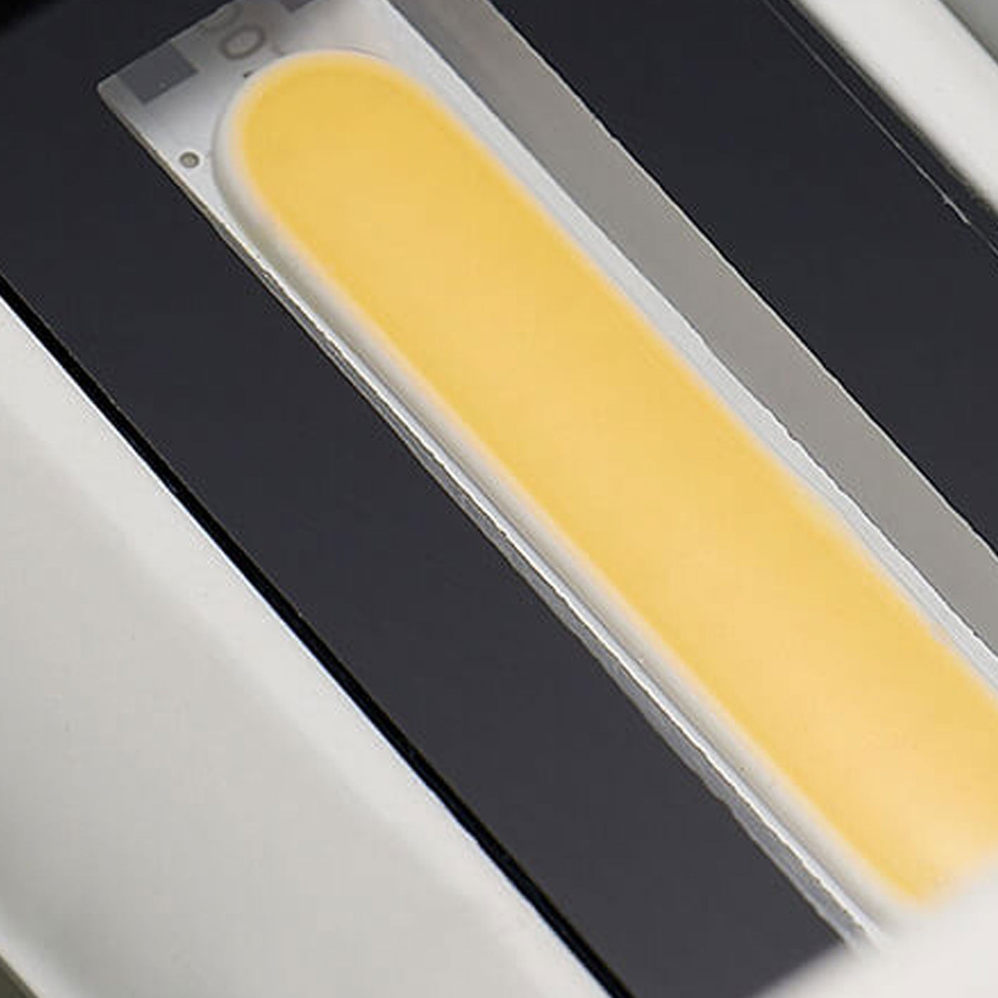 Yellow object on a black surface with a white background