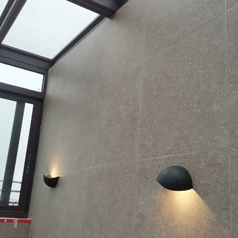 Two wall-mounted lights on a gray tiled wall with a glass ceiling above.