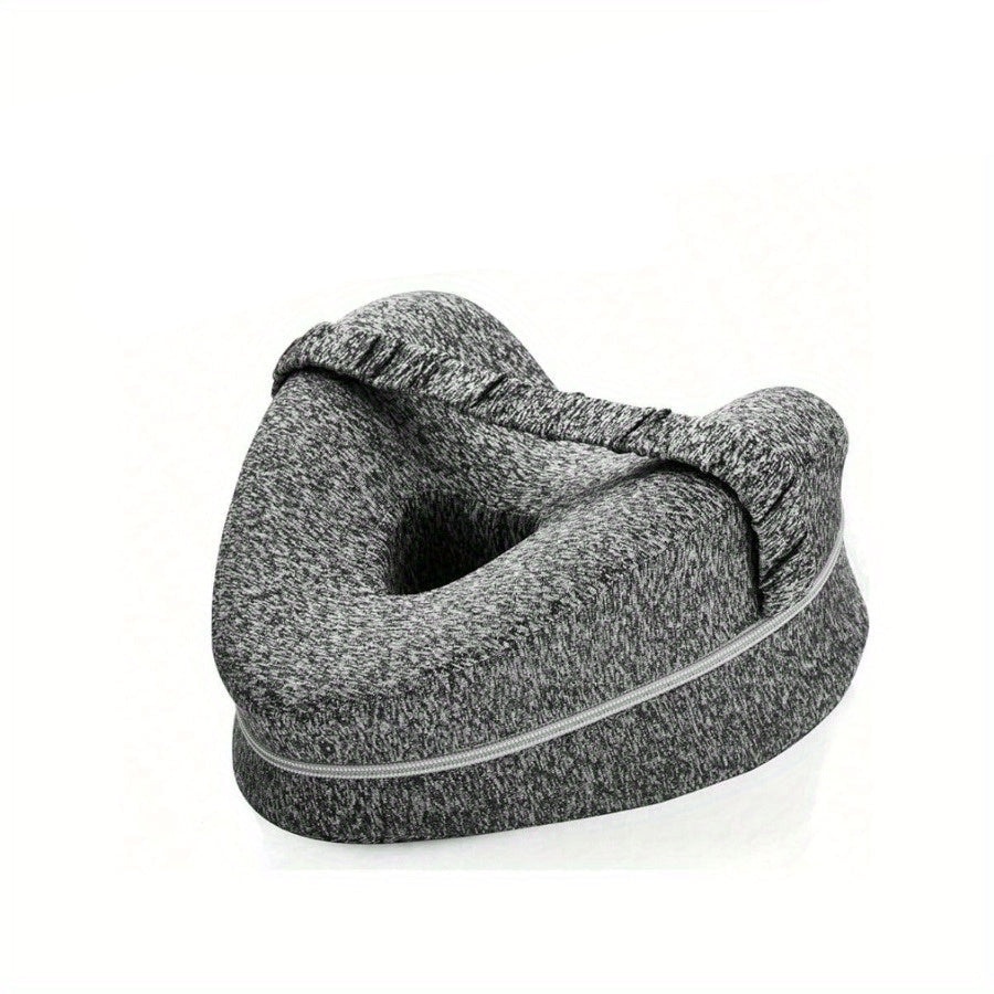 Gray travel pillow with a woman lying on a bed in the background
