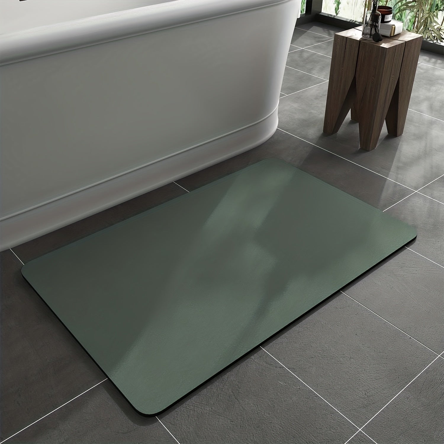 Green bath mat on a tiled bathroom floor next to a bathtub.
