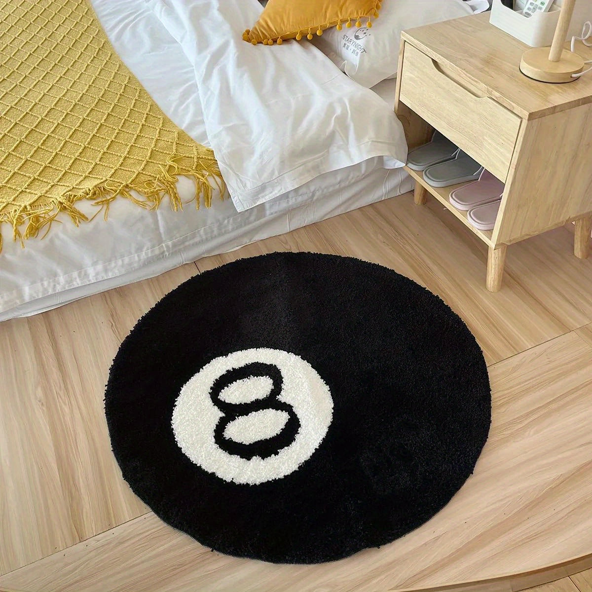 Round black rug with a white circle and number eight on a wooden floor in a bedroom.