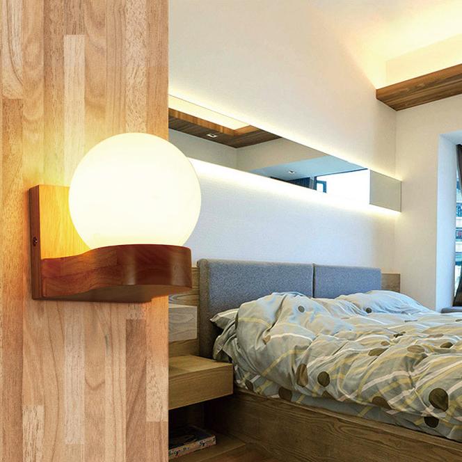 Wooden wall sconce with a round light bulb in a bedroom setting.