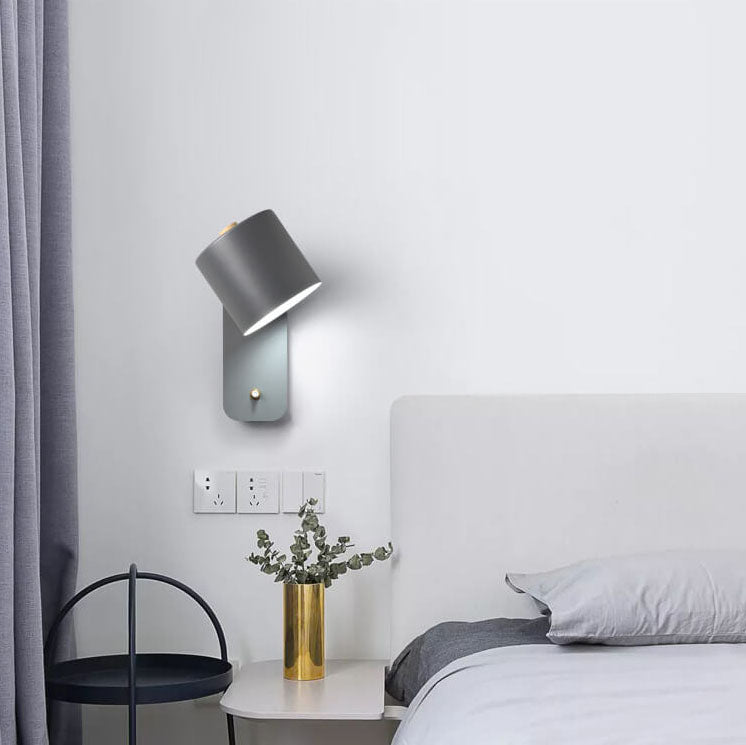 Modern bedroom with gray wall lamp, bed, and small table with plant