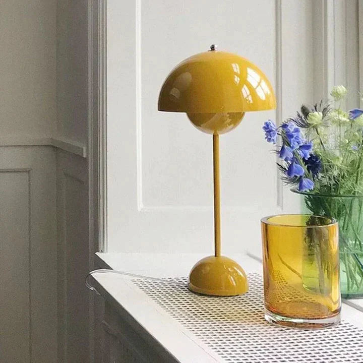 Yellow lamp and glass on a windowsill with flowers in the background