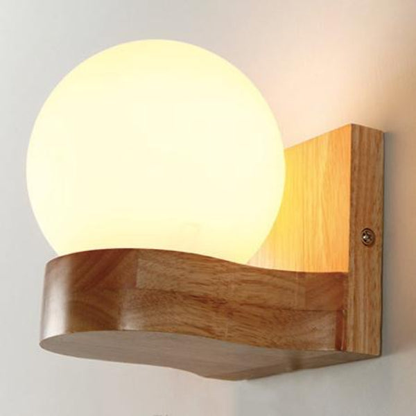 Wooden wall sconce with a round glass shade on a light gray background