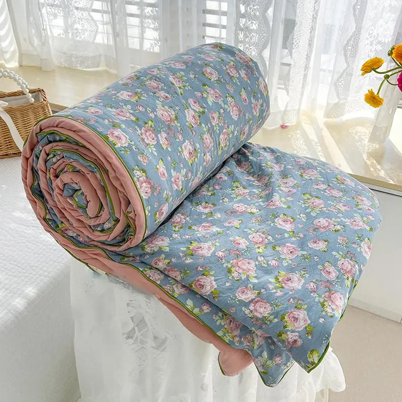 Roll of floral-patterned fabric on a bed with white curtains in the background