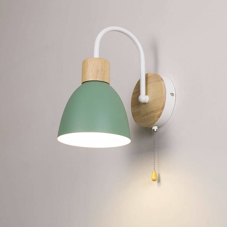 Wall lamp with green shade and wooden fixture on a plain wall
