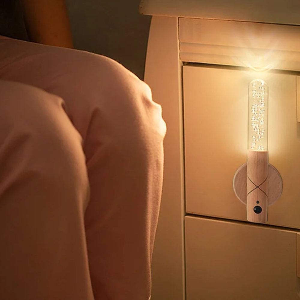 Person lying in bed with a nightlight on a wooden nightstand