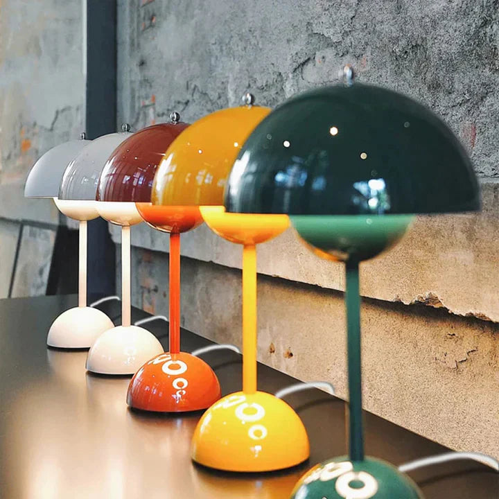 Colorful table lamps on a wooden surface with a concrete wall background