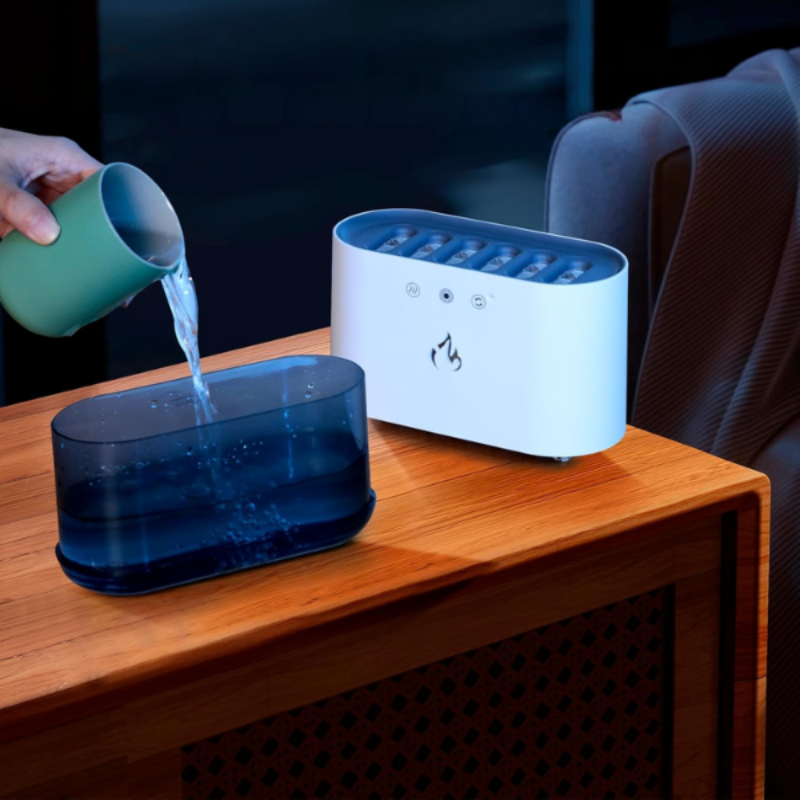 Person pouring water into a blue container next to a white electronic device on a wooden surface.