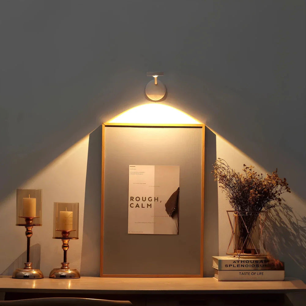 Wall-mounted light fixture casting a warm glow on a framed picture and decor items.