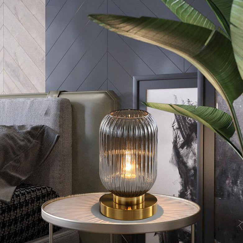 Decorative table lamp with ribbed glass shade on a side table in a living room setting.
