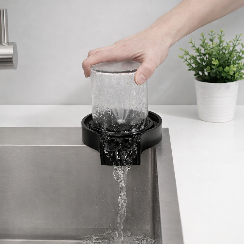 Person rinsing a glass under a faucet with water flowing into a sink.