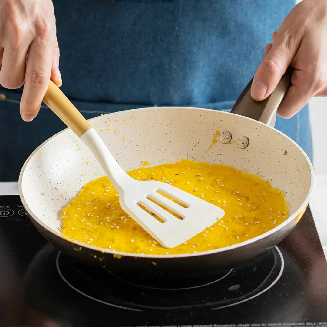 Person cooking eggs in a pan with a spatula on a stovetop