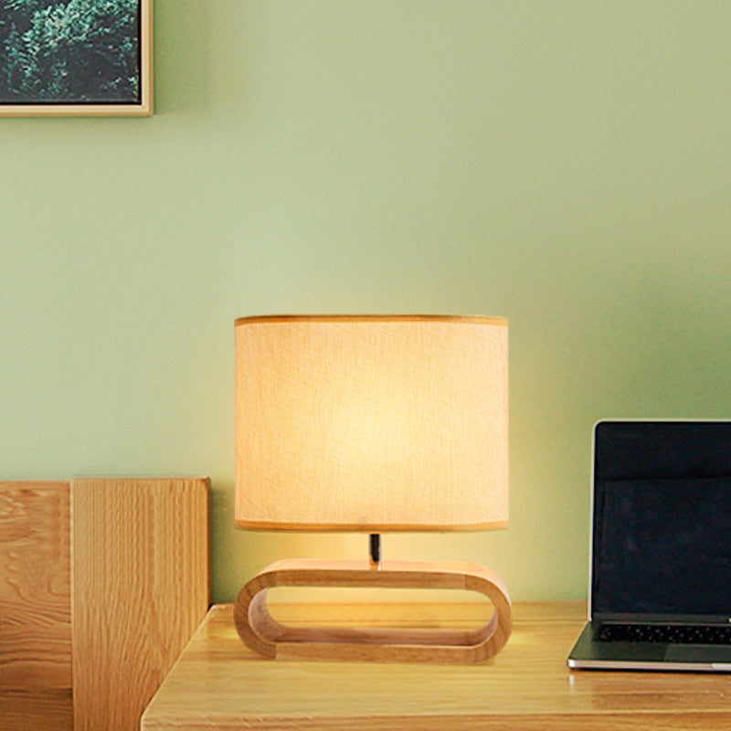 Table lamp on a wooden desk with a laptop against a light green wall