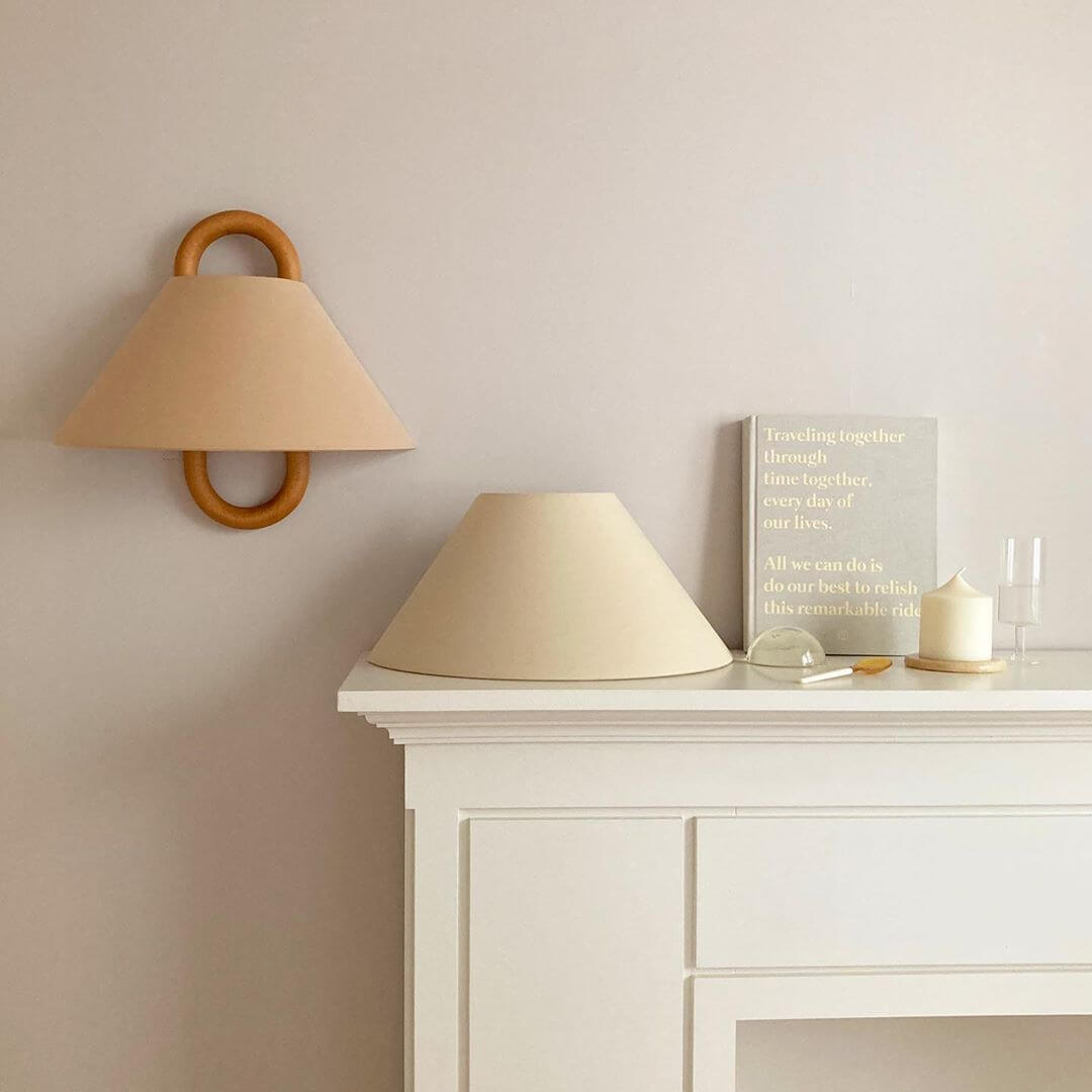 Beige wall lamp and table lamp on a white surface with a neutral wall background