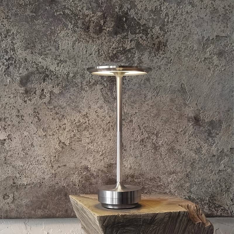 Modern silver lamp on a wooden block against a textured gray wall