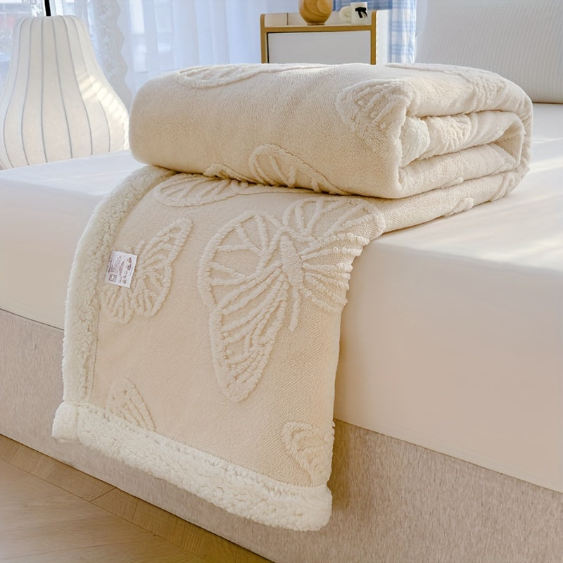 Beige textured blanket on a bed with a visible brand label.