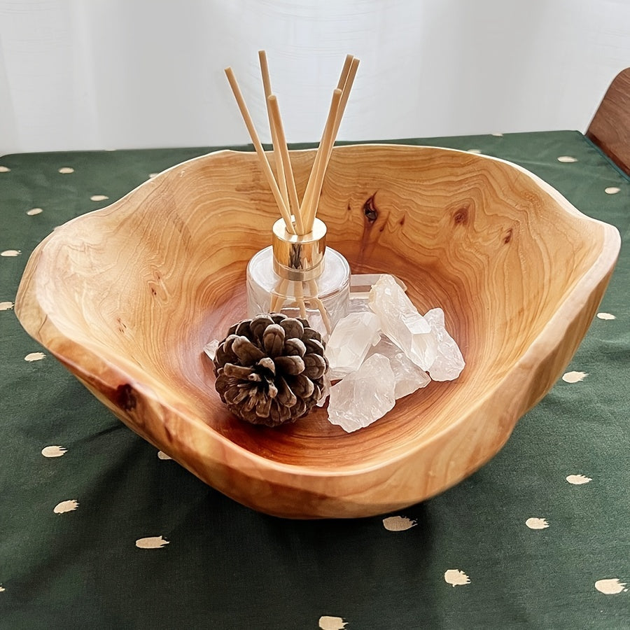 Wooden bowl with decorative items including a pine cone, crystals, and reed diffuser on a green tablecloth.