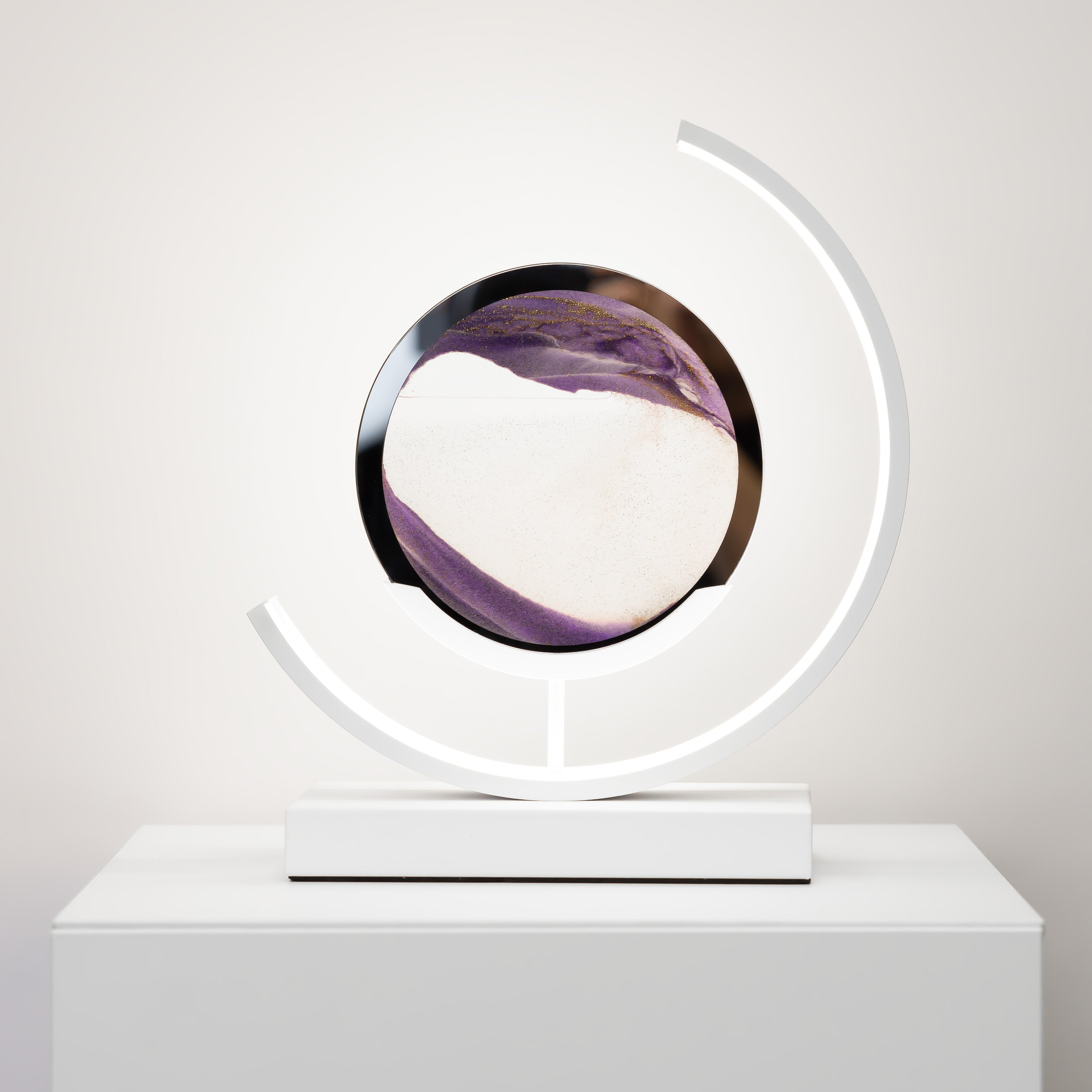 Modern decorative object with a circular design on a white pedestal against a light gray background