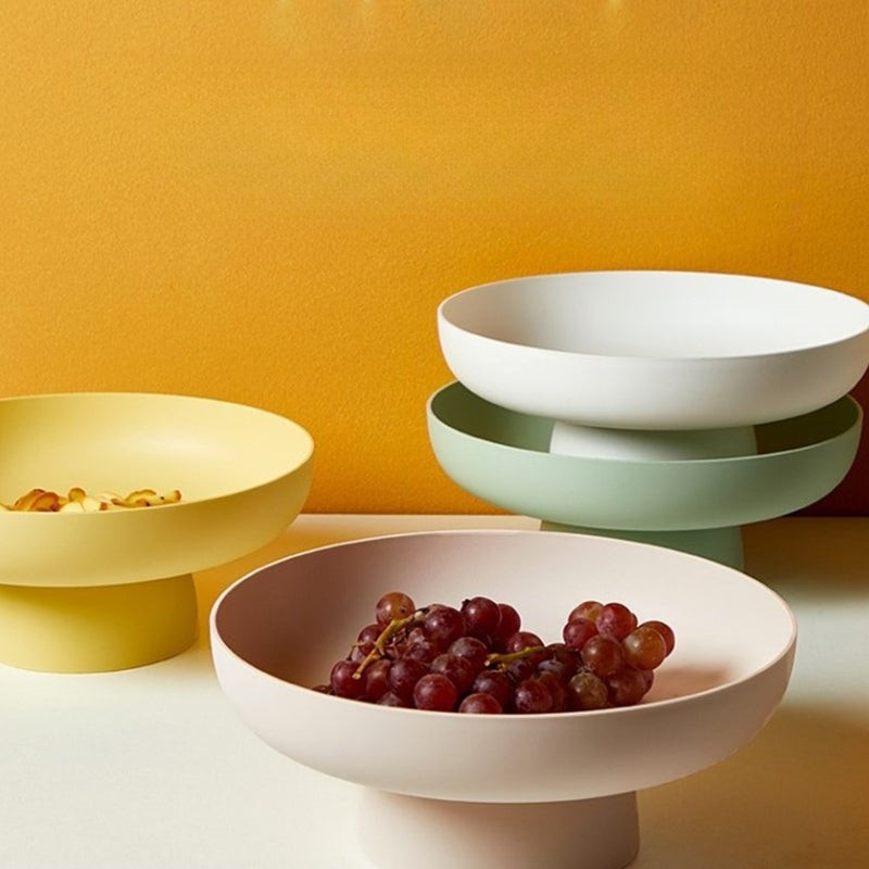 Set of colorful bowls with grapes on a yellow background