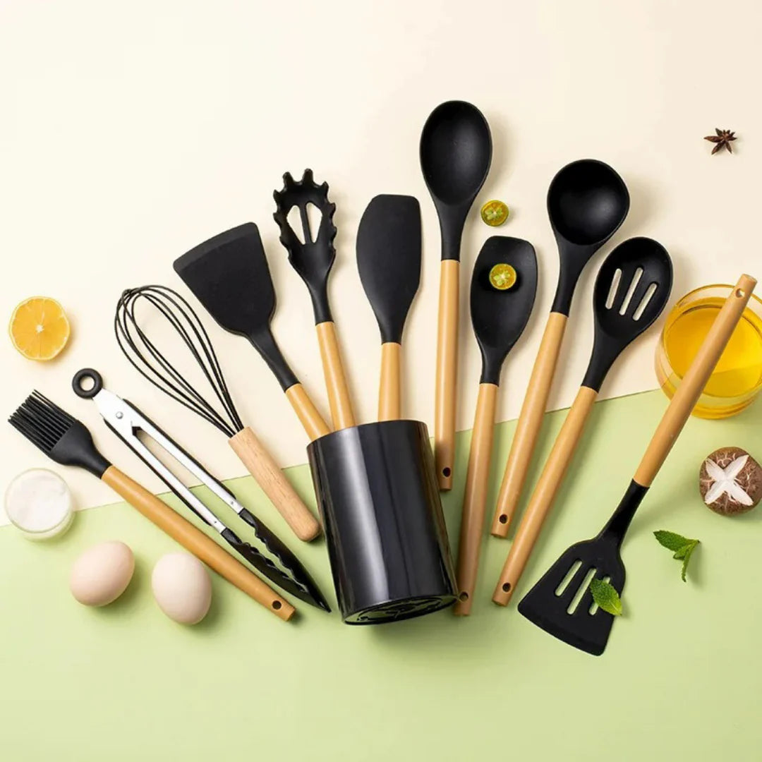 Set of black kitchen utensils with wooden handles on a light green background