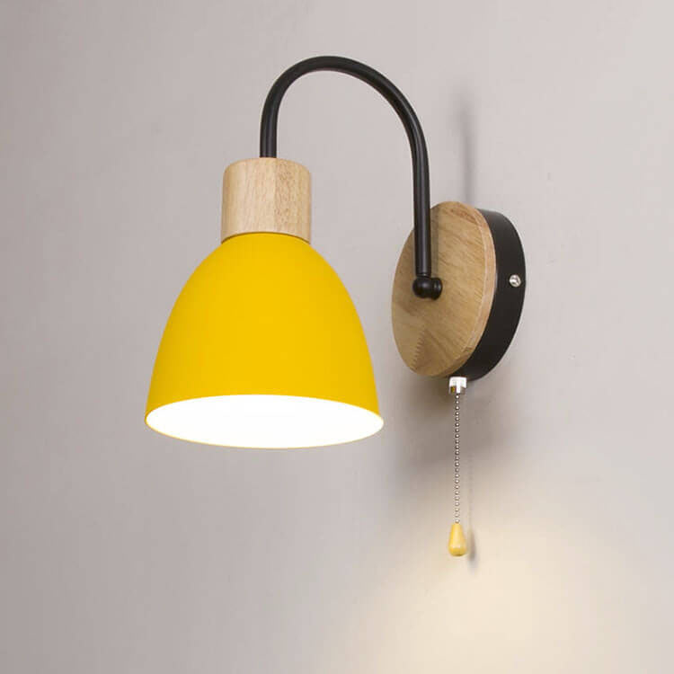 Wall-mounted lamp with yellow shade and wooden base on a gray wall