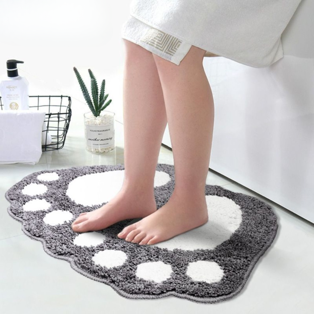 Person standing on a gray bath mat with white circles in a bathroom setting.