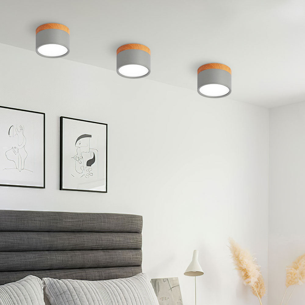 Three ceiling lights in a room with a bed and wall art.